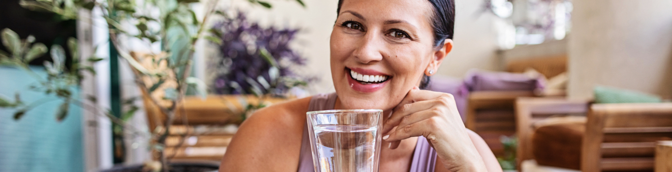 Employee holding a glass of water and smiling at inspiring wellbeing activities in the workplace